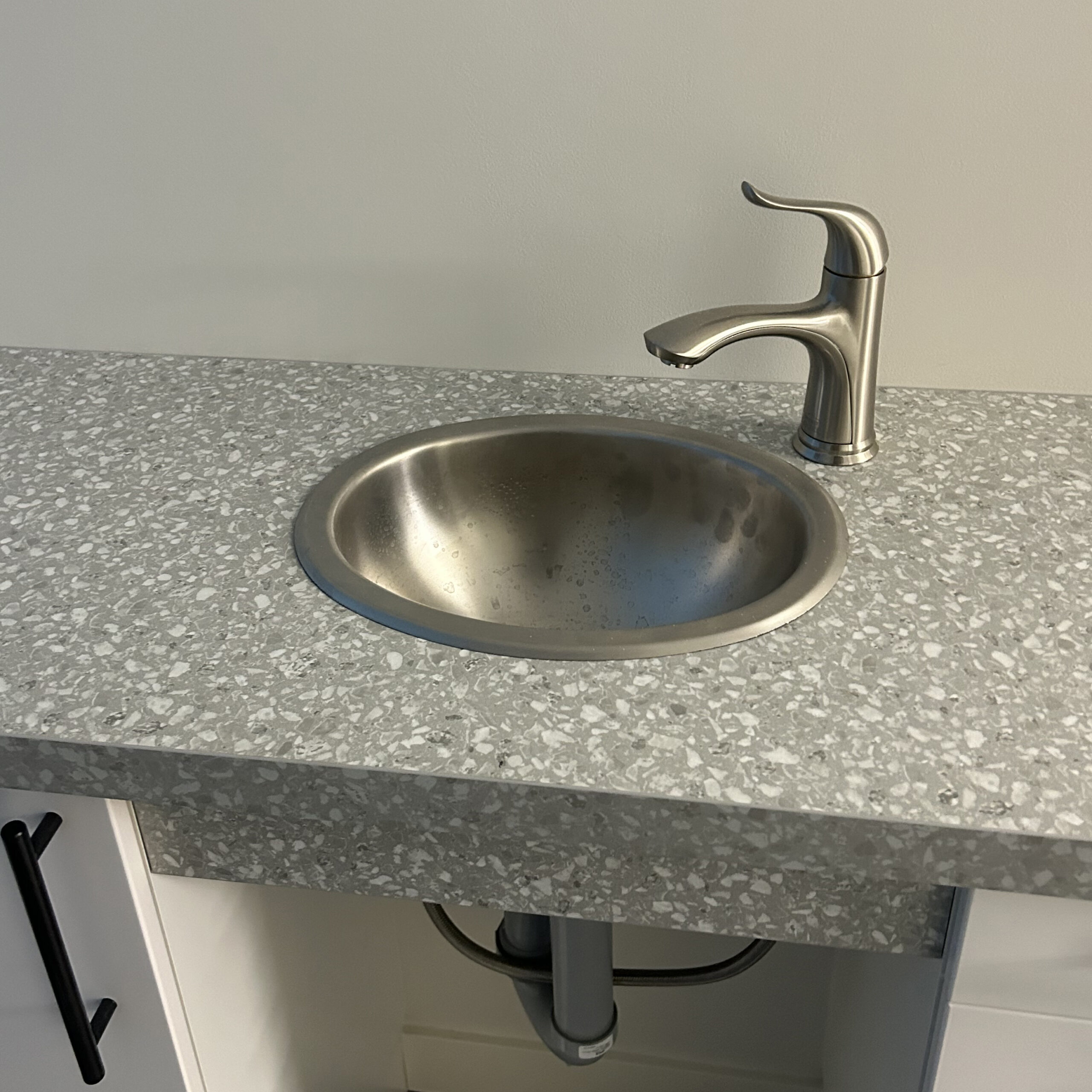 A sink with pipes visible under the counter